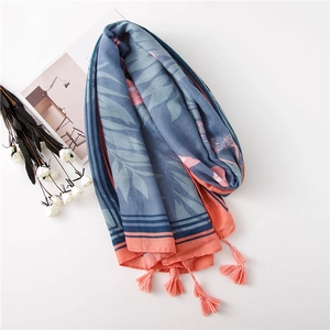 Détail d'une écharpe bleue et rose avec motif tropical et glands orange vif