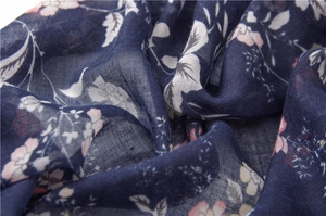 Dettaglio di sciarpa in cotone blu scuro con stampa floreale, nappe e tessuto traspirante