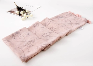 Close-up of pink cotton scarf with dandelion prints and fringe tassels detail