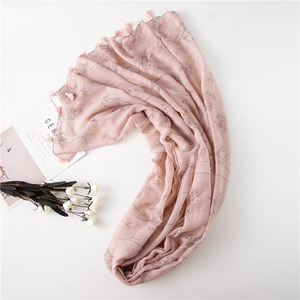 Detail of light pink floral scarf with dandelion prints and fringe edges on white background