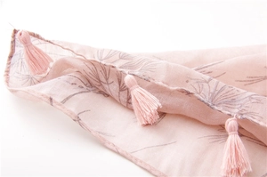 Detail of pink floral print scarf featuring delicate cotton fringe and breathable fabric
