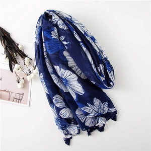 Detail of blue floral print scarf with fine fringe tassels on white background