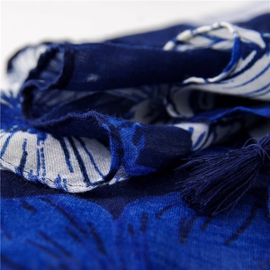 Close-up of blue floral print fabric with matching tassels on a cotton linen scarf