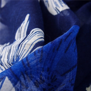 Macro shot of navy blue scarf fabric showing detailed white floral print and fine linen texture