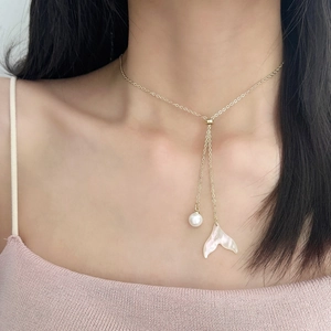 Collier doré élégant avec perle et pendentif queue de poisson en nacre sur un mannequin