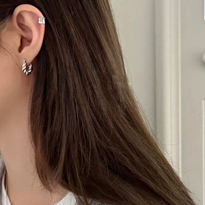 Elegant twisted silver hoop earring and minimalist ear cuff shown on a female model