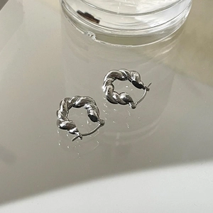 Macro view of silver twisted rope hoop earrings with glossy metallic texture and clasp