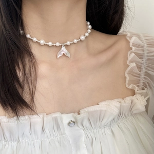 Elegant pearl necklace with a shell fishtail pendant worn on a model's neck