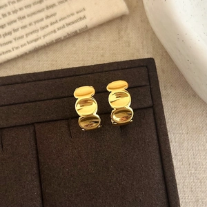 Détail macro de boucles d'oreilles C dorées géométriques avec finition polie sur velours
