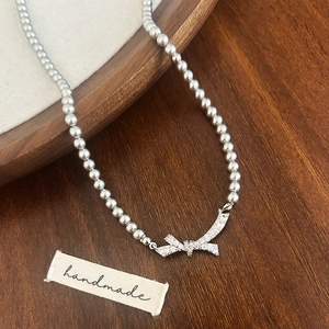 Vue détaillée du collier en perles avec pendentif nœud serti sur fond bois rustique