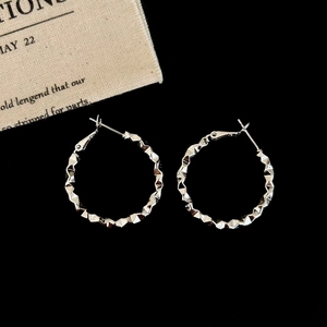 Macro shot of silver hoop earrings featuring multifaceted 3D pyramid textured metal finish