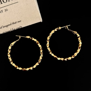 Detailed macro shot of gold hoop earrings with a unique faceted geometric texture