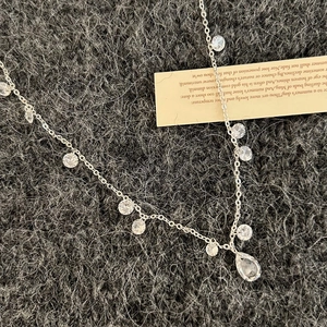 Elegant silver necklace with round zircon drops and a teardrop pendant on gray velvet
