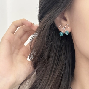 Elegant silver bow and teal cherry stud earrings on model for a chic summer look