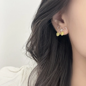 Elegant silver bow earrings with yellow heart pendants worn for a summer minimalist look