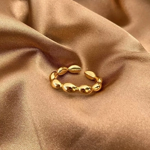 Bague ouverte dorée style croissant avec texture brillante sur tissu en soie marron