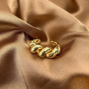Bague ouverte dorée torsadée minimaliste sur satin de luxe pour un look chic