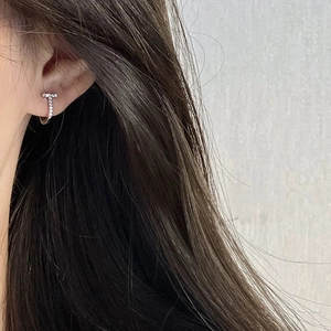 Elegant T-shaped silver earrings with pavé zircons worn on a model's earlobe