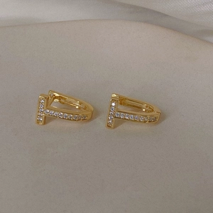 Detailed macro view of gold-plated T-shape earrings featuring micro-paved cubic zirconia