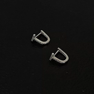 Macro shot of silver T-shaped earrings with micro-inlaid cubic zirconia on black background
