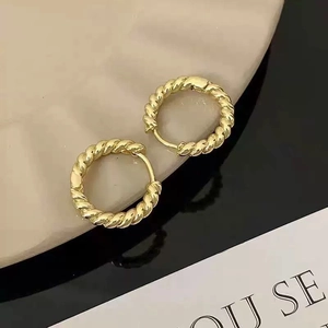 Macro shot of minimalist gold twisted rope hoop earrings with glossy polished finish