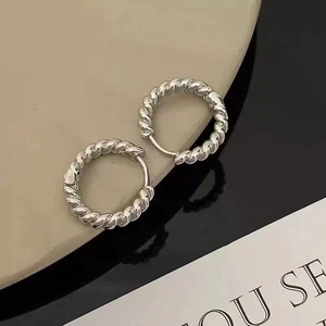 Macro shot of silver twisted hoop earrings featuring vintage braided rope texture