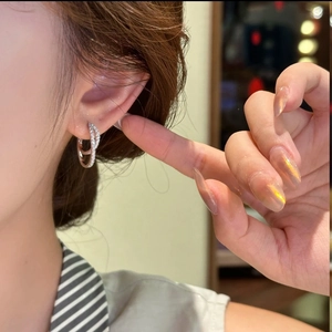 Minimalist double-layer silver hoop earrings with cubic zirconia worn on ear lobe