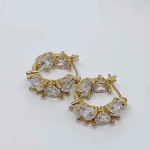 Detailed view of gold hoop earrings featuring heart-shaped cubic zirconia in a prong setting