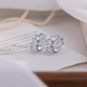 Macro detail of silver heart zircon earrings with multi-prong setting on white background