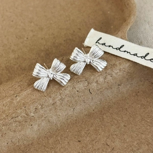 Silver bow stud earrings with zircon inlay on handmade textured background