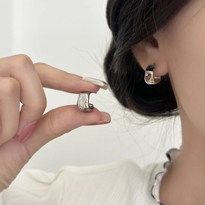 Boucles d'oreilles irrégulières en argent avec zircons colorés portées à l'oreille