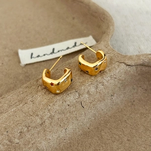 Détail de boucles d'oreilles dorées en C avec zircons colorés et étoiles gravées
