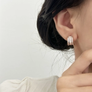 Élégantes créoles en C or rose avec zircons et incrustations blanches sur mannequin