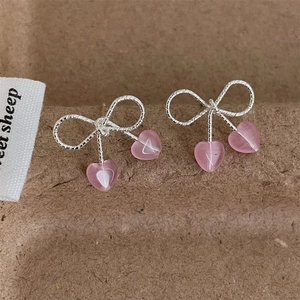 Silver bow knot earrings with soft pink heart opal pendants on textured background