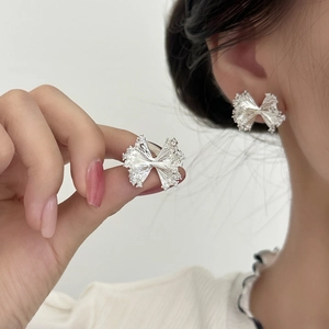 Elegant silver textured ribbon stud earrings with zircon details on a female model