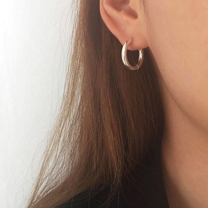Minimalist silver hoop earrings with polished finish shown on a model side view