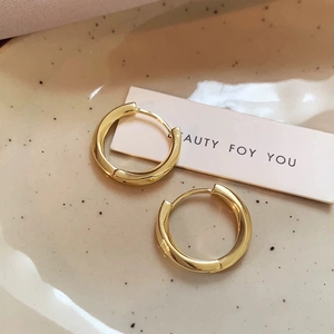 Minimalist gold twisted hoop earrings displayed elegantly on a ceramic jewelry tray