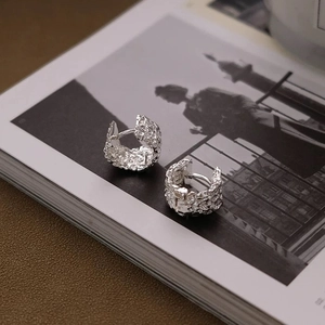 Silver textured hoop earrings with a crumpled foil effect on a lifestyle magazine background