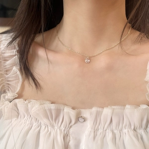 Elegant gold chain necklace with a single teardrop zircon pendant worn by a model
