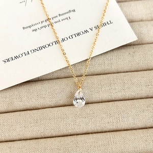 Macro detail of elegant teardrop zircon pendant on a dainty gold-tone necklace chain