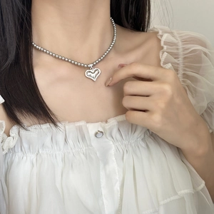 Collier à billes argenté élégant avec pendentif cœur minimaliste porté par mannequin