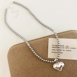 Collier de perles élégant avec pendentif coeur argenté et fermoir mousqueton sur fond