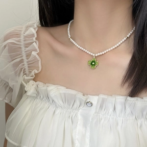 Elegant pearl choker necklace with green crystal clover pendant for sophisticated women