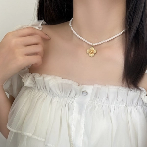 Elegant pearl necklace with golden flower pendant shown on model neck for luxury style