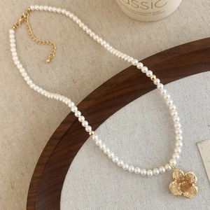 Detailed close-up of a pearl necklace with a vintage gold crystal flower pendant