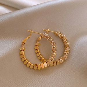 Detailed close-up of gold hoop earrings featuring textured metal and shimmering crystals