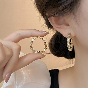 Detailed close-up of gold hoop earrings with sparkling paved rhinestones on a model