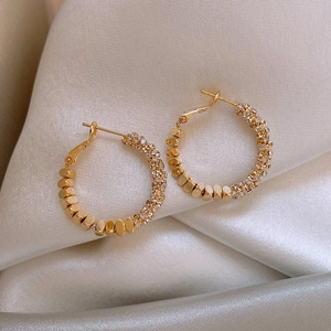 Detailed macro view of gold hoop earrings with faceted beads and sparkling pavé crystals