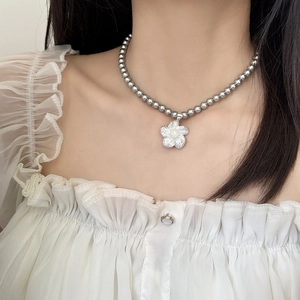 Collier de perles élégant avec pendentif fleuri étincelant porté par un mannequin