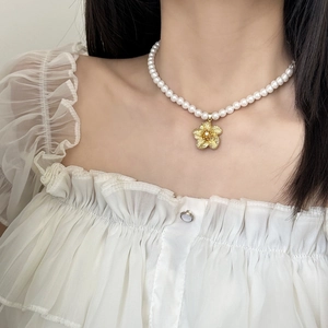 Collier élégant en perles avec un pendentif fleur dorée sur le cou d'un modèle
